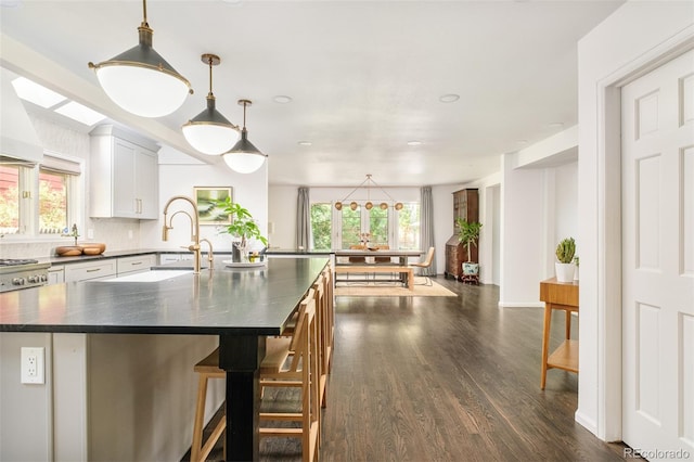 40 S Dexter St, Denver, CO 80246 - kitchen featuring dark countertops, dark wood-style floors, healthy amount of natural light, and a center island with sink