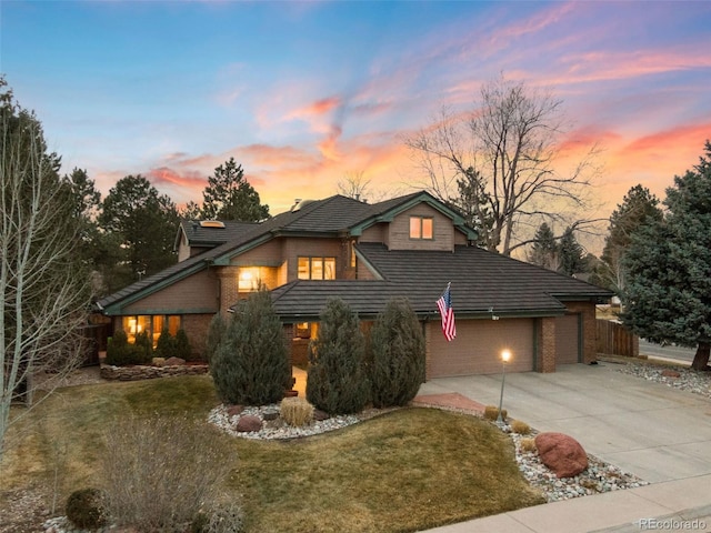 view of front facade featuring brick siding, a lawn, concrete driveway, and fence