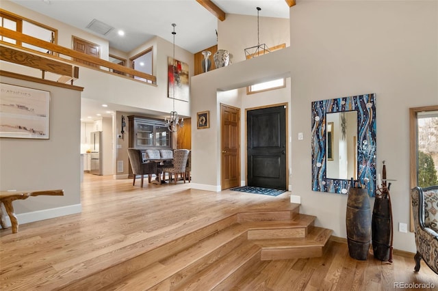 foyer entrance featuring beam ceiling, wood finished floors, visible vents, and baseboards