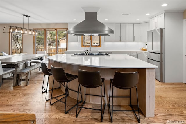 kitchen featuring island exhaust hood, visible vents, appliances with stainless steel finishes, and light wood-style flooring