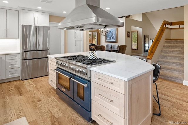 kitchen featuring a kitchen island, a kitchen bar, light wood-style flooring, island exhaust hood, and stainless steel appliances