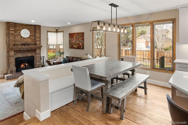 dining space with a brick fireplace, plenty of natural light, recessed lighting, and light wood-type flooring