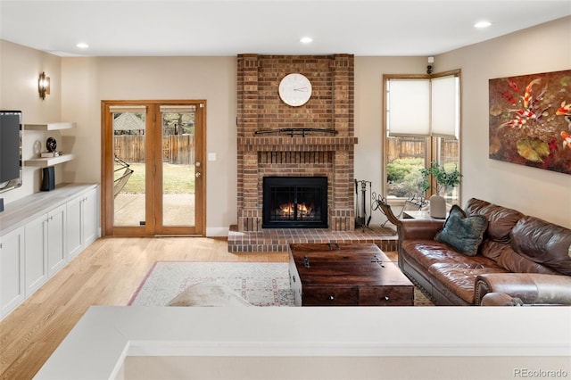 living room with recessed lighting, a fireplace, and light wood-style floors