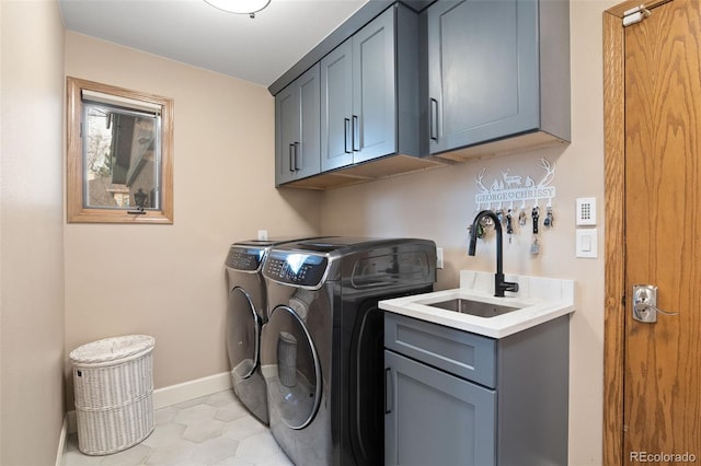 laundry area with light tile patterned floors, baseboards, separate washer and dryer, cabinet space, and a sink