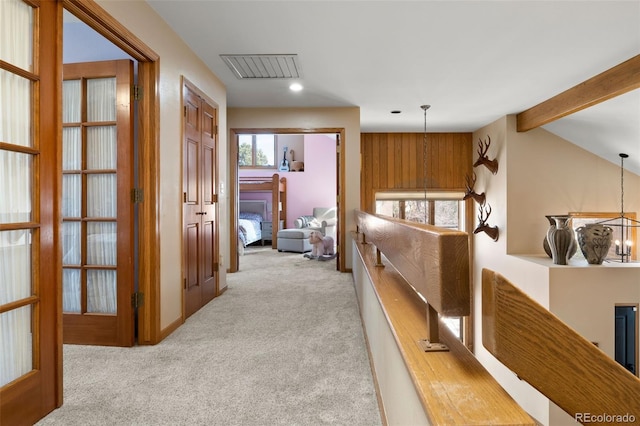 hallway with visible vents, vaulted ceiling with beams, carpet, a chandelier, and an upstairs landing