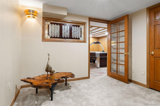 hallway with light carpet, french doors, and baseboards