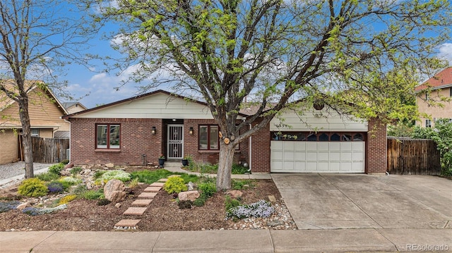 6235 W Floyd Ave, Denver, CO 80227 - view of front facade featuring concrete driveway, brick siding, and a garage