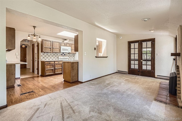 4490 Balsam St, Wheat Ridge, CO 80033 - unfurnished living room featuring light colored carpet, baseboard heating, a chandelier, french doors, and baseboards