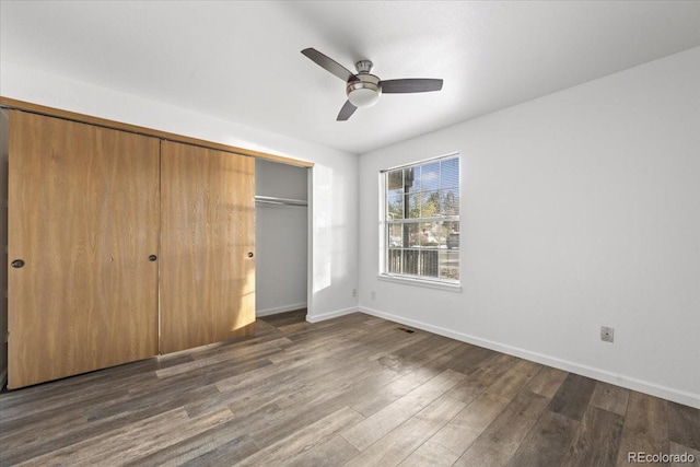 unfurnished bedroom featuring ceiling fan, dark hardwood / wood-style floors, and a closet