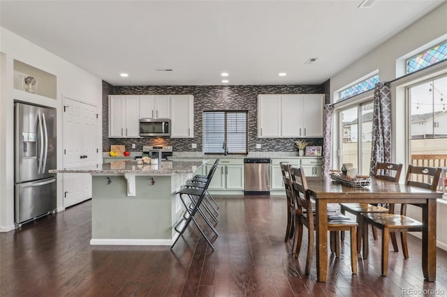 kitchen with decorative backsplash, a kitchen island, appliances with stainless steel finishes, and dark wood finished floors