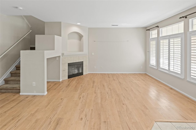 8399 Stonybridge Cir, Highlands Ranch, CO 80126 - unfurnished living room with wood finished floors, stairs, a tiled fireplace, and recessed lighting