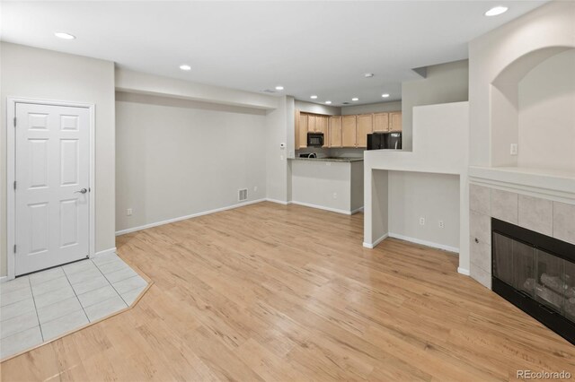 8399 Stonybridge Cir, Highlands Ranch, CO 80126 - unfurnished living room with light wood-style flooring, a tile fireplace, and recessed lighting