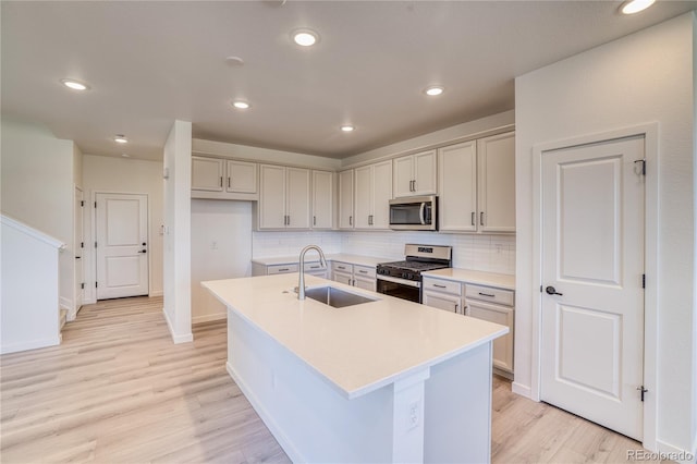 kitchen with a sink, light wood-style floors, tasteful backsplash, and stainless steel appliances