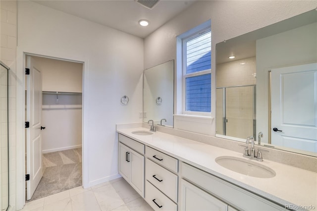 full bath featuring a walk in closet, a shower stall, double vanity, and a sink