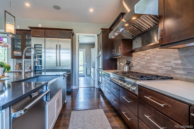 230 S Big Meadow Trl, Franktown, CO 80116 - kitchen with wall chimney exhaust hood, decorative backsplash, stainless steel appliances, dark brown cabinets, and dark wood-style floors