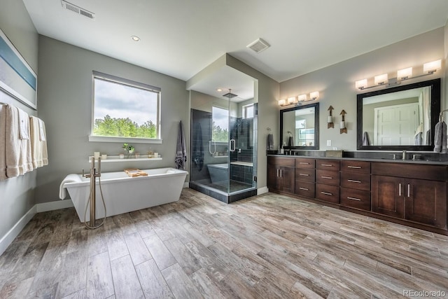 230 S Big Meadow Trl, Franktown, CO 80116 - bathroom featuring a shower stall, double vanity, a soaking tub, wood finished floors, and baseboards