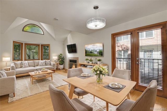 dining space featuring a tile fireplace, light wood-type flooring, and plenty of natural light