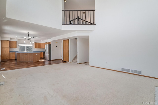 unfurnished living room featuring a high ceiling, dark hardwood / wood-style floors, and an inviting chandelier