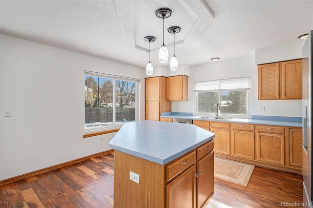 kitchen with sink, a kitchen island, hanging light fixtures, dark hardwood / wood-style flooring, and a textured ceiling