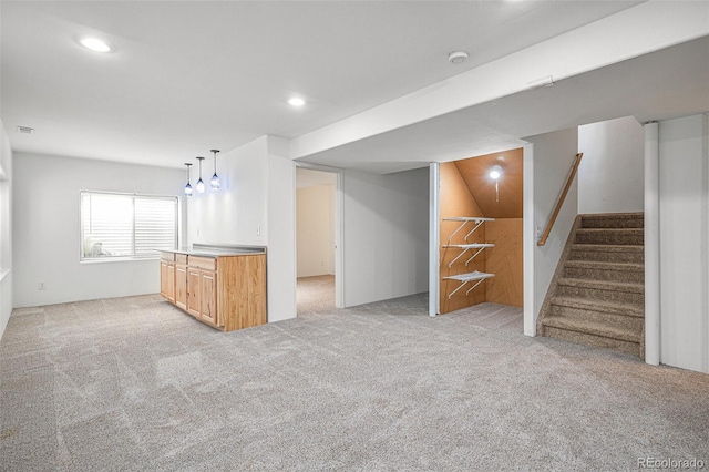 kitchen with light carpet, light brown cabinets, and hanging light fixtures