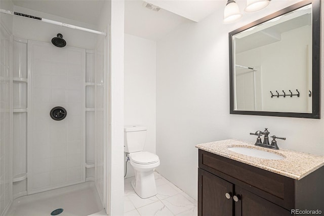 bathroom with vanity, toilet, and tiled shower