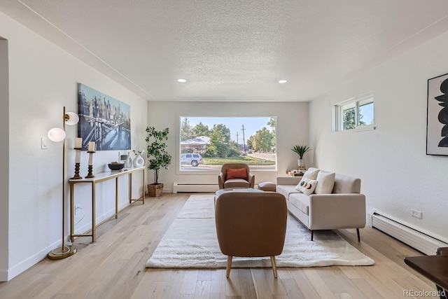 living room with light hardwood / wood-style flooring, a textured ceiling, and baseboard heating