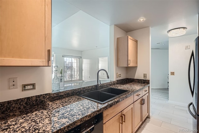 kitchen with dishwasher, light brown cabinets, sink, dark stone countertops, and stainless steel refrigerator