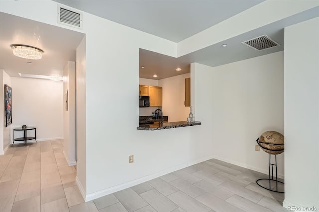 interior space featuring light brown cabinetry and dark stone countertops