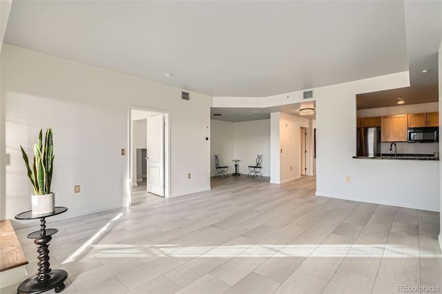 300 W 11th Ave Unit 4F, Denver, CO 80204 - unfurnished living room with a sink, baseboards, and light wood-style flooring