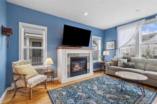 45 Bridge St, Breckenridge, CO 80424 - living room featuring a baseboard heating unit, a glass covered fireplace, wood finished floors, and baseboards