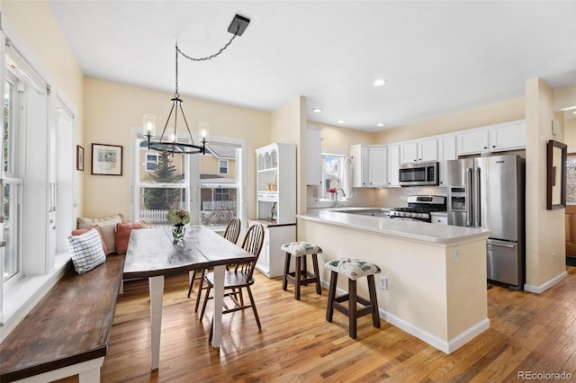 45 Bridge St, Breckenridge, CO 80424 - kitchen featuring stainless steel appliances, light wood finished floors, a chandelier, white cabinets, and a peninsula