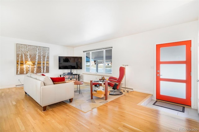 living room featuring light wood-style floors, a baseboard heating unit, and baseboards