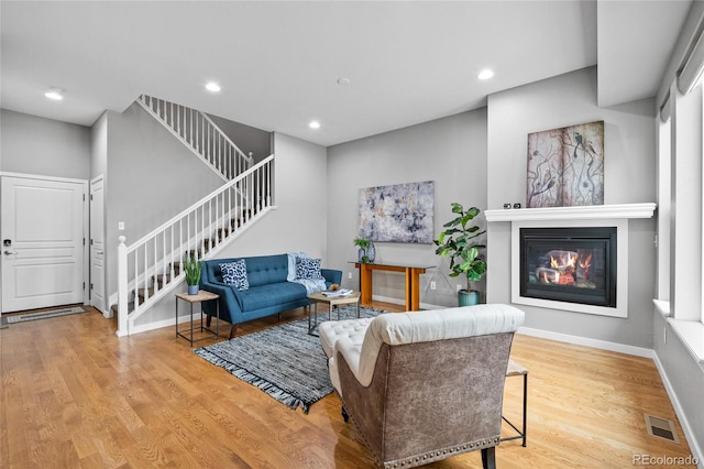 living area with stairway, wood finished floors, visible vents, and recessed lighting
