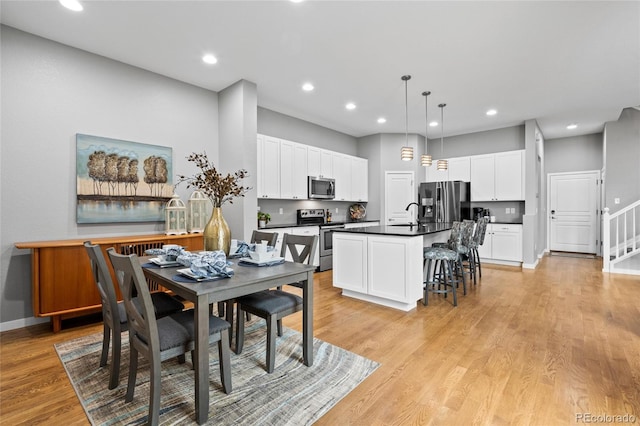 dining area with recessed lighting, light wood-type flooring, baseboards, and stairway