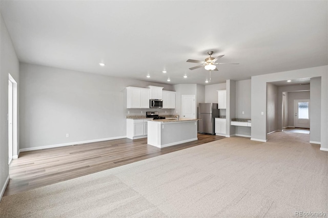 kitchen with white cabinets, ceiling fan, stainless steel appliances, and an island with sink