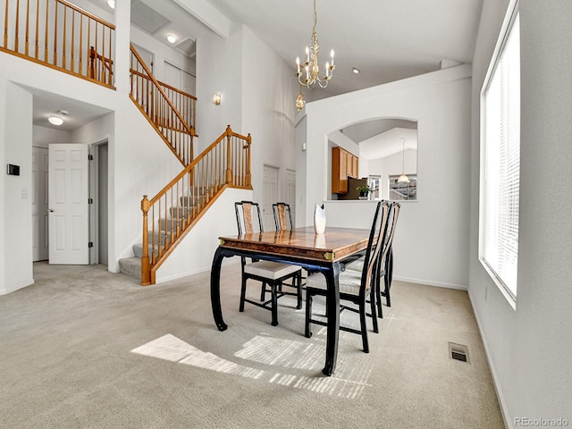 dining room with carpet, visible vents, stairway, and arched walkways