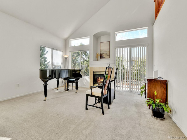 sitting room with baseboards, a tiled fireplace, high vaulted ceiling, and carpet floors