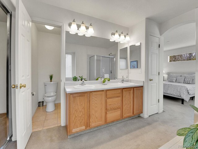 ensuite bathroom with a shower stall, toilet, double vanity, and a sink