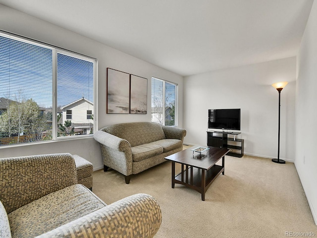living area with baseboards, light colored carpet, and plenty of natural light