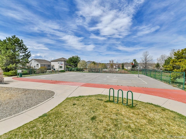 view of sport court featuring a lawn, a residential view, fence, and community basketball court