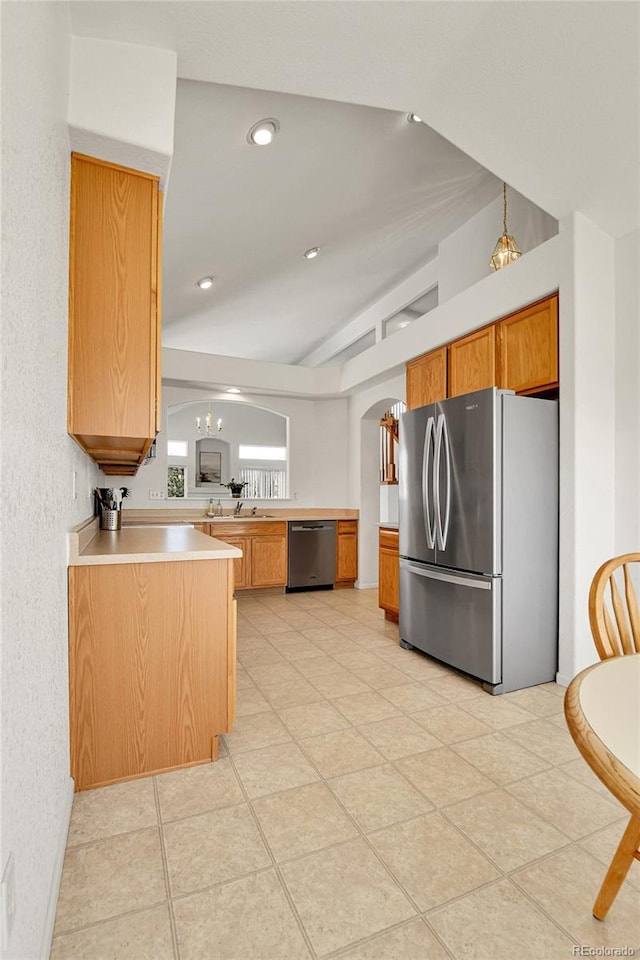 kitchen with a peninsula, lofted ceiling, stainless steel appliances, light countertops, and arched walkways