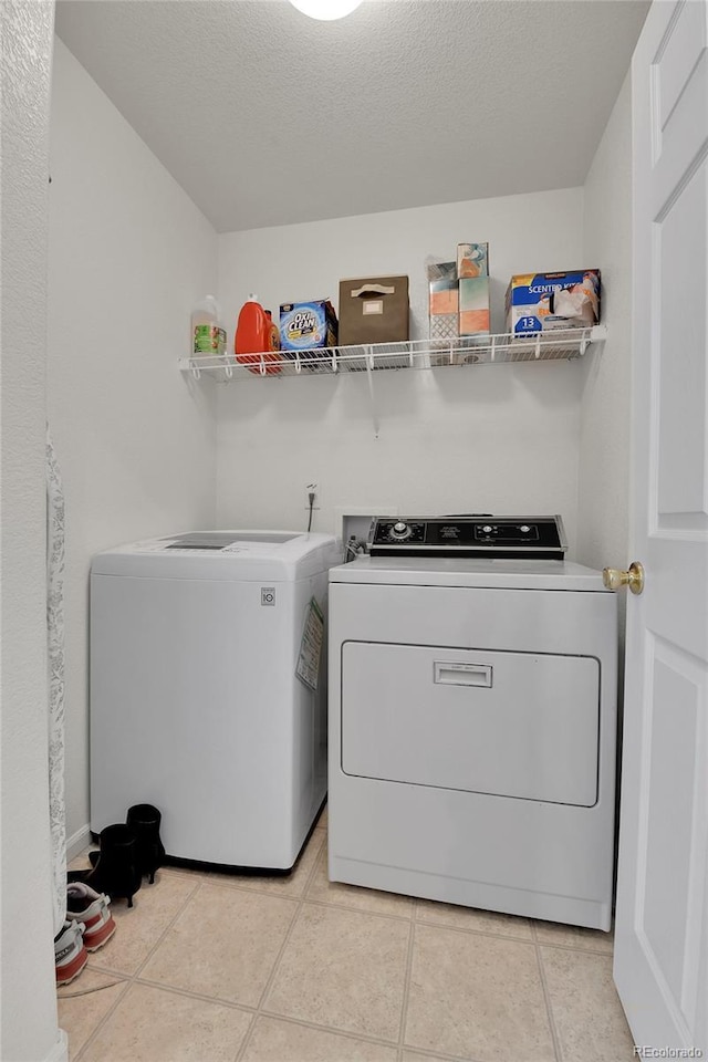 laundry area featuring light tile patterned floors, a textured ceiling, laundry area, and washer and dryer