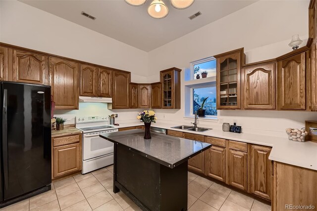 8370 Midsummer Ln, Elizabeth, CO 80107 - kitchen featuring freestanding refrigerator, electric stove, under cabinet range hood, light tile patterned floors, and glass insert cabinets