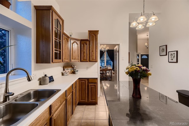 8370 Midsummer Ln, Elizabeth, CO 80107 - kitchen with a chandelier, glass insert cabinets, light tile patterned floors, decorative light fixtures, and brown cabinets