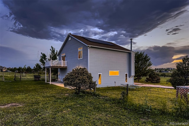 8370 Midsummer Ln, Elizabeth, CO 80107 - property exterior at dusk with roof mounted solar panels, a lawn, a wooden deck, and a patio area