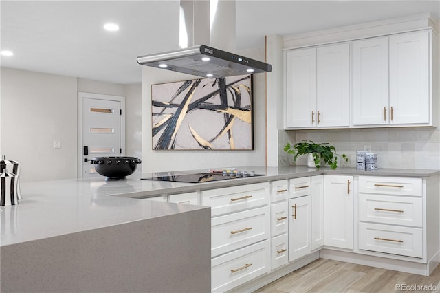 kitchen with island exhaust hood, black electric cooktop, white cabinets, recessed lighting, and light wood-style flooring