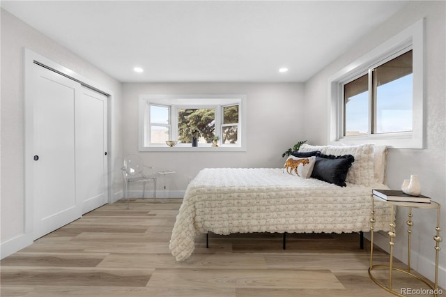 bedroom featuring wood finished floors, recessed lighting, a closet, and baseboards