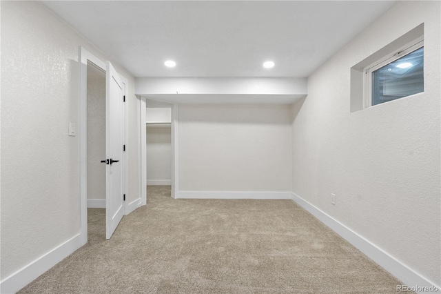 basement with carpet flooring, a textured wall, baseboards, and recessed lighting