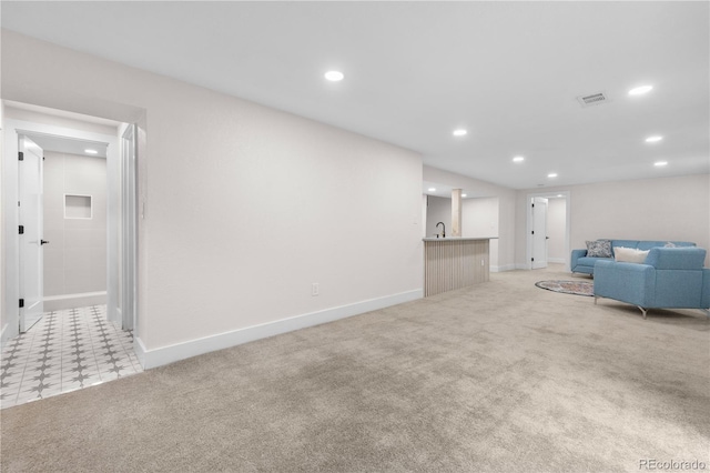 living room featuring recessed lighting, baseboards, bar with sink, and light colored carpet
