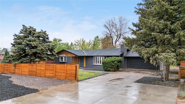 view of front of house with concrete driveway, roof with shingles, a garage, and a chimney